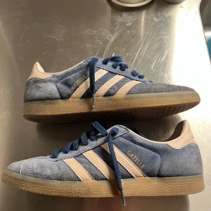 Adidas Gazelle blå/beige sneakers - Säljer ett par Adidas Gazelle sneakers i blå mocka. Säljer för att de har blivit för små. Köpta nya och inte speciellt använda. Det står storlek 45 men passar 44. Hör av dig vid minsta fundering. 