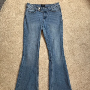 Bootcut jeans från Vero Moda - Snygga blå bootcut jeans från Vero Moda med klassisk femficksdesign och dubbla silverknappar i midjan. Jeansen har en högre midja och är tillverkade i mjukt denimtyg som ger en skön passform. Perfekt för dig som gillar retrovibbar och stilren look.💙(okej liten i storlek känns som XS)