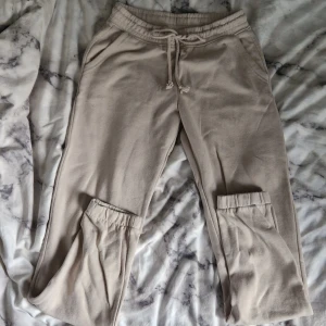 Beige mjukisbyxor med snörning - Beiga mjukisbyxor med elastisk midja och snörning framtill. Byxorna har sidfickor och är tillverkade i mjukt bomullsmaterial. Perfekta för chill dagar eller när du vill vara extra bekväm. Säljer då dom är för korta för mig. Har lite noppor.