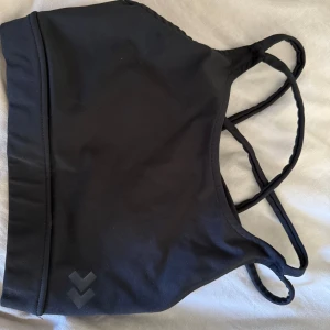 Svart sportig linnetopp från 157 - Säljer en svart linnetopp från 157 med tunna korsade axelband i ryggen. Toppen är i stretchigt material och har en sportig look, perfekt för träning eller chill. Enkel design med diskret logga framtill. Sitter tajt och bekvämt på kroppen.