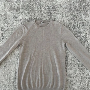 Beige stickad tröja från John Henric - Snygg beige stickad tröja från John Henric i storlek S. Tröjan har rund halsringning och långa ärmar, perfekt för lager-på-lager. Enkel och stilren design som funkar till många outfits. Den är 100% merinoull och i väldigt bra skick. Mitt pris 400kr nypris 1200kr