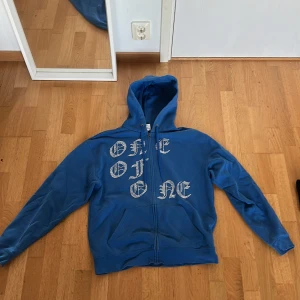 Blå hoodie One of One med rhinestone - Unik hoodie från One of One. Tröjan har dragkedja, huva med snörning. Så snygg med rhinestone (inga av stenarna saknas) Perfekt för dig som vill sticka ut. Den säljer inte längre vilket gör den unik