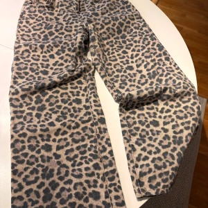 Leopardmönstrade jeans från Perfect Jeans - Säljer ett par unika jeans från Perfect Jeans i storlek 36 med snyggt leopardmönster. Byxorna har klassisk femficksdesign och raka ben. Färgerna går i beige och svart, och materialet är klassisk jeanskvalitet. Perfekta för dig som vill sticka ut med din stil.