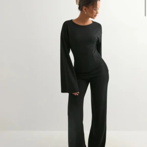 Svart långärmad topp med vida ärmar - Säljer en svart långärmad topp med riktigt snygga vida ärmar. Toppen har en rund halsringning och är figurnära över kroppen, vilket ger en clean och stilren look. Perfekt att matcha med både jeans och kostymbyxor. Materialet känns mjukt och stretchigt.