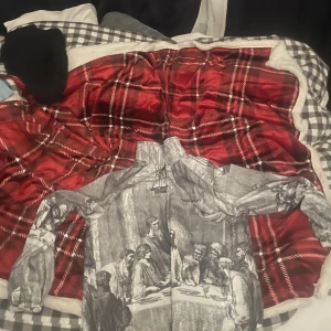 Grå bomberjacka med konstmotiv - Unik grå bomberjacka med svartvitt konstmotiv som föreställer en klassisk måltidsscen. Jackan har resår vid ärmslut och midja samt hög krage. Perfekt för dig som vill sticka ut med en kreativ och konstnärlig stil.