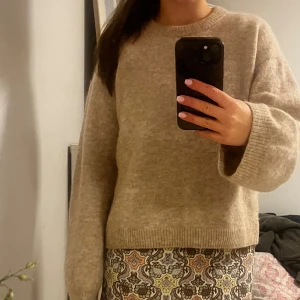 Beige stickad tröja med rund hals - Mysig beige stickad tröja med rundad hals och långa ärmar. Tröjan har en loose passform och ribbade muddar vid ärmslut och nederkant. Perfekt för dig som gillar enkel och chill stil, funkar till jeans eller kjol.