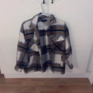 Rutig overshirt höst jacka från ZARA XS - Overshirt jacka från ZARA i rutigt mönster med beige, bruna, blå och vita toner. Jackan har klassisk krage, knäppning framtill och två bröstfickor med lock. Perfekt lager-på-lager-plagg för höst och vår då den är ganska tunn.