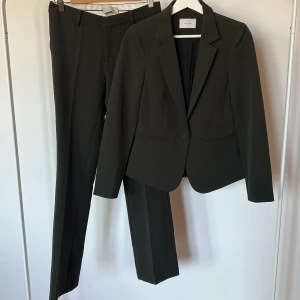 Mörkgrå kostym från Neo Noir XS - Snygg mörkgrå kostym från Neo Noir kavaj XS & byxor S. Setet består av en klassisk kavaj med en knapp och figurnära passform samt matchande raka kostymbyxor. Materialet är mjukt och stretchigt med 96% polyester och 4% elastan. Perfekt för dig som gillar stilrena och moderna looks.