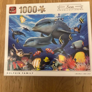 Dolphin Family - Färgglatt 1000-bitars pussel med motiv av delfiner, havssköldpaddor och tropiska fiskar i ett levande undervattenslandskap. Perfekt för dig som gillar havets djur och vill ha en rolig utmaning att lägga ensam eller med vänner.