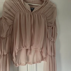 Beige volangblus från Missguided - Supersöt beige blus från Missguided med voluminösa, långa ärmar och volangdetaljer. Blusen har omlottkänsla, v-ringning