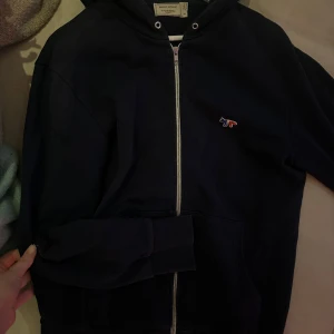 Maison Kitsuné  - Snygg mörkblå hoodie från Maison Kitsuné med dragkedja och huva.  Saknar dock snöret i luvan men annars superbra skick. Kostar 2400kr ny