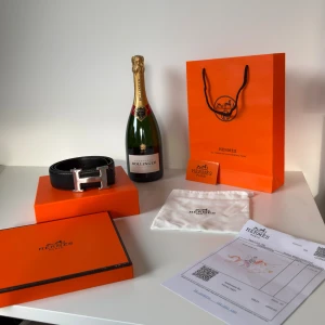 Svart H skärp/bälte med H-spänne - Exklusivt svart bälte från H med ikoniskt H-spänne i silverfärgad metall. Tillverkat i äkta skinn och levereras med originalförpackning, dustbag och kvitto. Perfekt accessoar för att lyfta din outfit med lyxig känsla och klassisk design.