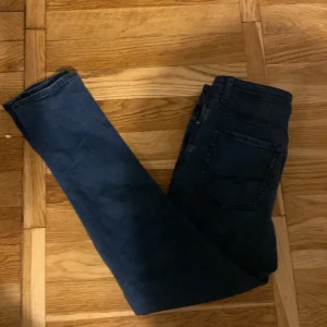 Mörkblå skinny jeans från Jack & Jones - Snygga mörkblå jeans från Jack & Jones med klassisk femficksdesign och smal passform. Jeansen har normal midja, dragkedja och knapp framtill. Materialet är mjukt och stretchigt jeans, perfekt för en stilren look.