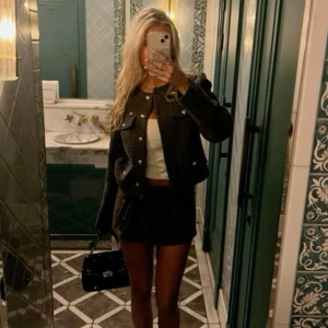 Mörkgrön cardigan med knappar - Snygg mörkgrön cardigan med guldiga knappar framtill och två bröstfickor. Jackan är croppad och har en klassisk rund halsringning. Materialet är stickat och ger en cool textur. Första bilden lånad på en liknande