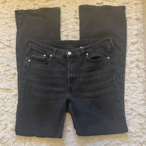 Svarta bootcut jeans high waist - Svarta jeans med bootcut och hög midja, klassisk femficksdesign och snygga sömmar. Jeansen är tillverkade i denim och har en stilren look som passar till sneakers eller boots. Perfekt för dig som gillar en tidlös och cool stil. Jeansen är välanvända men i bra skicka. Säljer eftersom de är för stora