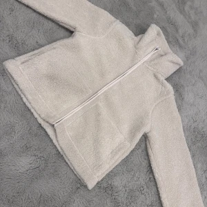 Beige teddyjacka från 157, XS - Säljer en beige teddyjacka från 157 i storlek XS. Jackan har två stora fickor framtill, hög krage och dragkedja hela vägen. Perfekt för dig som gillar mysiga och stilrena plagg med enkel design. Säljer pågrund av att den varit för kort för mig. 