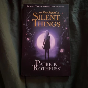 The Slow Regard of Silent Things - En mystisk och poetisk berättelse om Auri, en ung kvinna som lever i de hemliga tunnlarna under universitetet. Boken bjuder på en unik och drömlik atmosfär, perfekt för dig som gillar fantasy och gåtfulla karaktärer. Upptäck en värld fylld av hemligheter och magi!