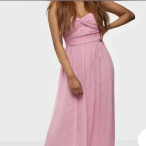 Ljusrosa långklänning från NLY Eve - Supersöt ljusrosa långklänning från Nelly med smala avtagbara axelband och twistad detalj vid bysten. Klänningen har ett flowy fall och är tillverkad i ett tunt, lätt material som känns luftigt. Perfekt för dig som vill ha en romantisk look med extra volym i kjolen. Dragkedjan behöver bytas till en ny eller knappar eller vad man tycker passar💕