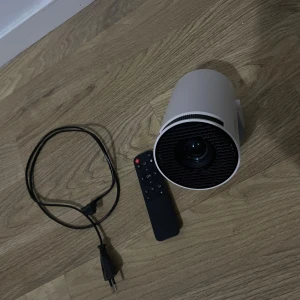 Lqwell Smart Projektor - Lqwell är en kompakt och portabel smart projektor med fjärrkontroll och strömkabel. HDMI och USB-portar för enkel anslutning. Enheten ser ut att vara i mycket gott skick utan synligt slitage. Perfekt för film, spel och presentationer. Helt ny används 7 gånger max. Pris går att diskutera.
