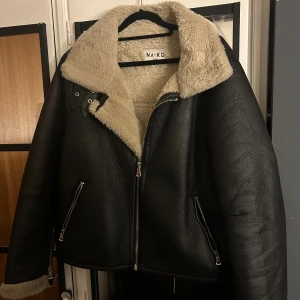 Svart fusk skinnjacka från NA-KD - Säljer en svart fusk skinnjacka från NA-KD med beige fuskpälsfoder. Jätte fin och varm passar perfekt till vintern. Den är använd några gånger men är fortfarande väldigt fin och hel.