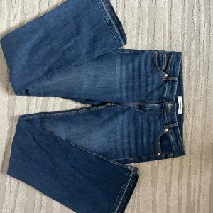 Wide jeans från Kappahl i mörkblå denim - Snygga mörkblå jeans från Kappahl med breda ben och klassisk femficksdesign. Jeansen har dragkedja och knapp framtill, kontrastsömmar och raka bakfickor. Perfekt för dig som gillar en loose och trendig look med mycket rörelsefrihet. Jeansen saknar dock dragkedjans drag men de går självklart att laga. Jeansen är köpta secondhand. 