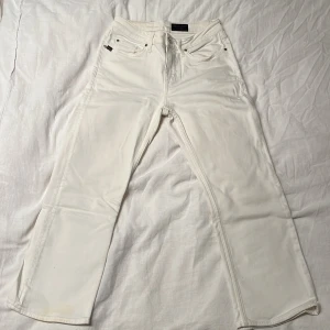 Vita jeans från Tiger of Sweden - Snygga vita jeans från Tiger of Sweden med klassisk femficksdesign. Byxorna är raka i modellen och tillverkade i en mjuk bomullsblandning med lite stretch för extra komfort. En liten fläck finns på jeansen