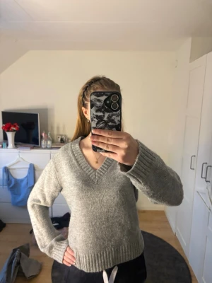 Stickad tröja - Mysig grå stickad tröja med V-ringning och långa ärmar. Tröjan är i storlek M men jag skulle nog säga att den är mer som S. Jag är 168cm lång och den passar mig perfekt. Endast använd ett par gånger! Pris kan diskuteras