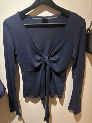 Mörkblå långärmad topp med knyt - Nästan ny topp, använd 1–2 gånger. Några små noppror som enkelt tas bort med nopprensare eller rakblad. Superfin med knytdetalj framtill, perfekt till både vardag och fest!