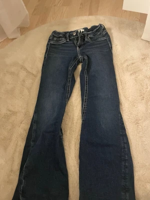 Blå bootcut jeans med kontrastsömmar - Snygga blå bootcut jeans från Gina tricot med vita kontrastsömmar och detaljerade bakfickor. Klassisk femficksmodell och låg midja. Perfekta för dig som gillar en avslappnad men trendig stil.