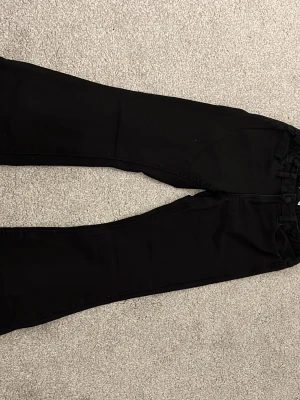 Svarta jeans från Lindex - Svarta jeans från Lindex med klassisk femficksdesign och bälteshällor. Jeansen har en rak passform och är tillverkade i ett mjukt bomullsmaterial med lite stretch för extra komfort. Perfekta att matcha med en hoodie eller t-shirt.