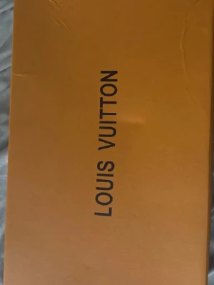 Louis Vuitton skor med originalbox kvitto finns - Lyxiga skor från Louis Vuitton levereras i original orange box med tillhörande dustbag. Perfekt för dig som vill ha en exklusiva skor från ett av världens mest ikoniska modehus.
