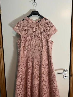 Rosa spetsklänning med blommönster från Esprit - Söt rosa klänning från Esprit i spets med blommigt mönster. Klänningen har korta ärmar, rund halsringning och dragkedja i ryggen. Perfekt för sommarens alla tillfällen och ger en romantisk vibe.