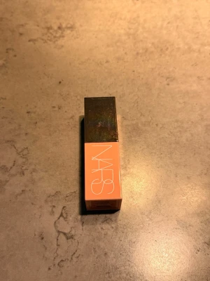 NARS Afterglow Lip Balm Orgasm - Flytande rouge från NARS i nyansen Orgasm, en persikotonad rosa med subtilt guldskimmer. Kommer i en stilren fyrkantig förpackning med svart lock och peachfärgad kropp. Perfekt för att ge kinderna en naturlig glow. Testar några få gånger, men det var fel färg för mig. 