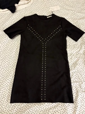 Svart klänning  - Snygg svart klänning från ZARA med silverfärgade nitar. Helt ny!