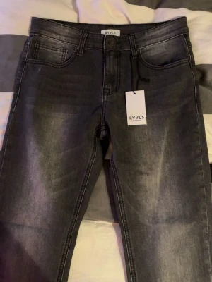 Straight fit jeans i off black från RYVLS  - Snygga straight fit jeans från RYVLS i färgen off black. Jeansen har klassisk femficksdesign, knapp och dragkedja i gylfen samt diskreta slitningar för en cool look. Perfekta för dig som gillar en smalare passform och stilren design. är även 29/30 men står 170