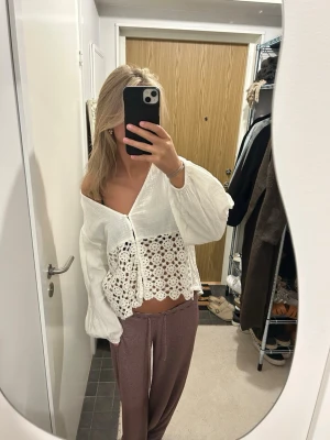 Vit blus med spets och v-ringning - Säljer en luftig vit blus med v-ringning och vida långärmar. Nedre delen av blusen har ett detaljerat spetsmönster och knappar framtill. Perfekt för dig som gillar romantisk och bohemisk stil.