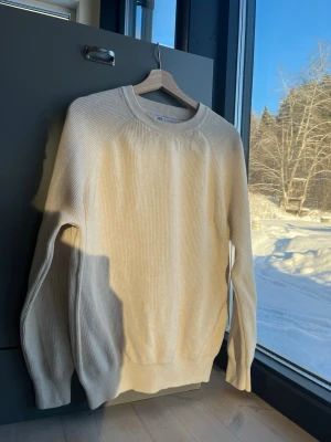 Beige ribbad tröja från Zara strl L - Snygg beige ribbad tröja från Zara med rund halsringning och långa ärmar. Tillverkad i mjukt material som ger en avslappnad men stilren look. Perfekt att matcha med jeans eller kjol för en enkel och trendig outfit.