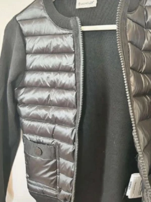 Moncler cardigan  - Moncler cardigan Säljer en svart Moncler jacka med vadderad framsida och stickade ärmar/rygg. Väldigt stilren, bekväm och perfekt för vår/höst eller som lager under kappa på vintern.  ✔ SPARSAMT ANDVÄND ✔ Bra skick, inga hål eller fläckar ✔ Dragkedja framtill + fickor ✔ Diskret Moncler-logga på ärmen  Säljes då den tyvärr inte kommer till användning. Skicka gärna meddelande vid frågor!