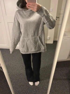 Grå hoodie från NLY Trend - Mysig grå hoodie från NLY Trend i storlek XS. Hoodien har en klassisk huva och en stor känguruficka framtill. Tillverkad i mjukt material med borstad insida för extra komfort. Perfekt för en avslappnad stil.
