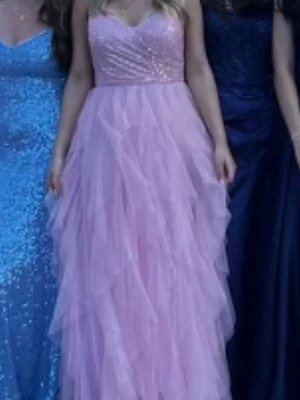 Rosa balklänning i tyll! - Säljer en lång, rosa klänning med flera lager volanger i tyll💗 Perfekt för speciella tillfällen som t.ex. bal! Den är köpt på lyckliga Storgatan i Sundsvall. Nypris 2400kr så jag lägger ut för 1200kr, men pris går att diskutera. Endast använd en kväll, den har inga defekter förutom två små fläckar nästan längst ner på den vänstra sidan, men dom är ganska ljusa och syns inte om man inte kollar noga. Den passar på mig som är 160cm lång men då hade jag även klackar på mig som är cirka 5cm höga🫶💗