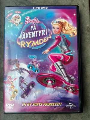 Barbie på äventyr i rymden dvd - Följ med Barbie på ett äventyr bortom denna värld!  Barbie och hennes trogna valp Popcorn ger sig ut på roliga och positivt lysande hoverboard äventyr över en vacker och avslappnad planet. En dag förändras allt när de dansande stjärnorna börjar blekna och saktar ner deras dans i skyn.  Finns på språk: Svenska, Danska, Norska, Finska, Engelska, Arabiska.  OBS!! skivorna är begagnade så det kan förekomma repor/hairlines på skivorna, men då jag kollar igenom alla filmer jag säljer