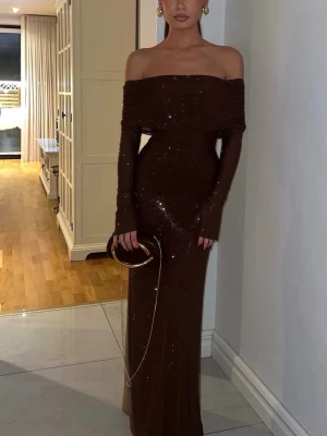 Brun glittrig offshoulder långklänning - Snygg brun långklänning med glittriga detaljer och offshoulder-design. Klänningen har långa ärmar och en figurnära passform som framhäver siluetten. Perfekt för dig som vill sticka ut med en elegant look.