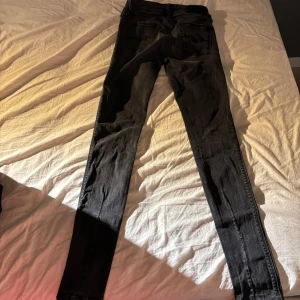 Svarta skinny jeans från Replay - Snygga svarta jeans från Replay med smal passform och klassisk femficksdesign. Jeansen har en mörk tvätt och raka bakfickor med diskreta detaljer. Perfekta för dig som gillar en tight och stilren look.