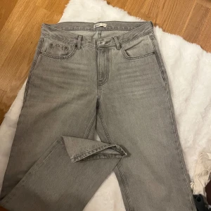 Grå jeans från Gina tricot perfect jeans, stl 40 - Säljer ett par grå jeans från gina tricot perfect jeans i storlek 40. Jeansen har klassisk femficksdesign, raka ben och normal passform. Tillverkade i bomull med snygg tvättad look och silverfärgad knapp framtill. Perfekta för en chill och stilren vardagsstil.