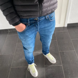 Dondup George - Säljer ett par blå skinny fit jeans från dondup i storlek 34. Jag är 184 och väger 77kg på bilden.  Jeansen har klassisk femficksdesign, normalhög midja och är tillverkade i stretchig denim för en tajt passform. Perfekta för dig som gillar en smal siluett och stilren look.