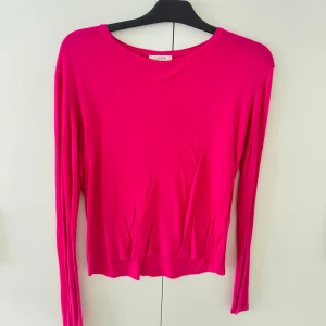 Ceriserosa långärmad tröja Lindex - Säljer en ceriserosa långärmad tröja från Lindex. Tröjan har en rund halsringning och är tillverkad i ett mjukt, stretchigt material som känns skönt mot huden. Perfekt för dig som gillar färg och enkel stil.