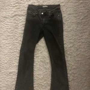 Mörkgråa bootcut jeans  - Snygga mörkgråa bootcut jeans från Gina i storlek 36. Jeansen har klassisk femficksdesign, knapp och dragkedja framtill samt en något utsvängd passform nertill. 
