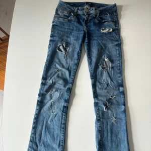 LTB Valerie blå slitna jeans W25 L30 - Säljer mina älskade blå jeans från LTB, modell Valerie, med snygga slitningar och hål på benen. Jeansen är i ett bra skick, har en svag missfärgning där bak vid vaden men inget jag någonsin lagt märke till. Bara hojta till vid fler frågor!❤️