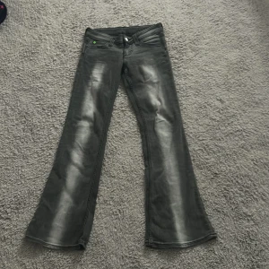 Svarta bootcut jeans med slitning - Snygga svarta jeans med bootcut passform och lätt slitning på benen. Klassisk femficksmodell med en grön detalj på myntfickan. Jeansen har låg midja och är tillverkade i ett stretchigt denimtyg för extra komfort. Pris kan diskuteras 