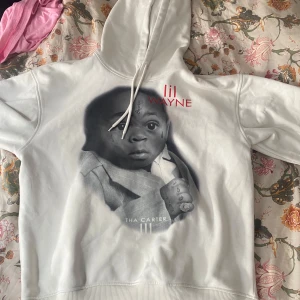 Vit Lil Wayne Tha Carter III hoodie - Säljer en vit hoodie från Lil Wayne med tryck av Tha Carter III på framsidan. Hoodien har huva med snörning och långa ärmar. Materialet är mjukt och skönt, perfekt för dig som gillar streetwear och vill sticka ut med en unik merch. Men den är stor för att vara en storlek small, bara så man vet det. 